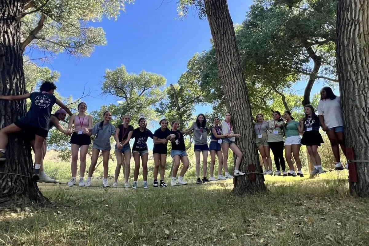 Girls Rule campers linking arms between two trees